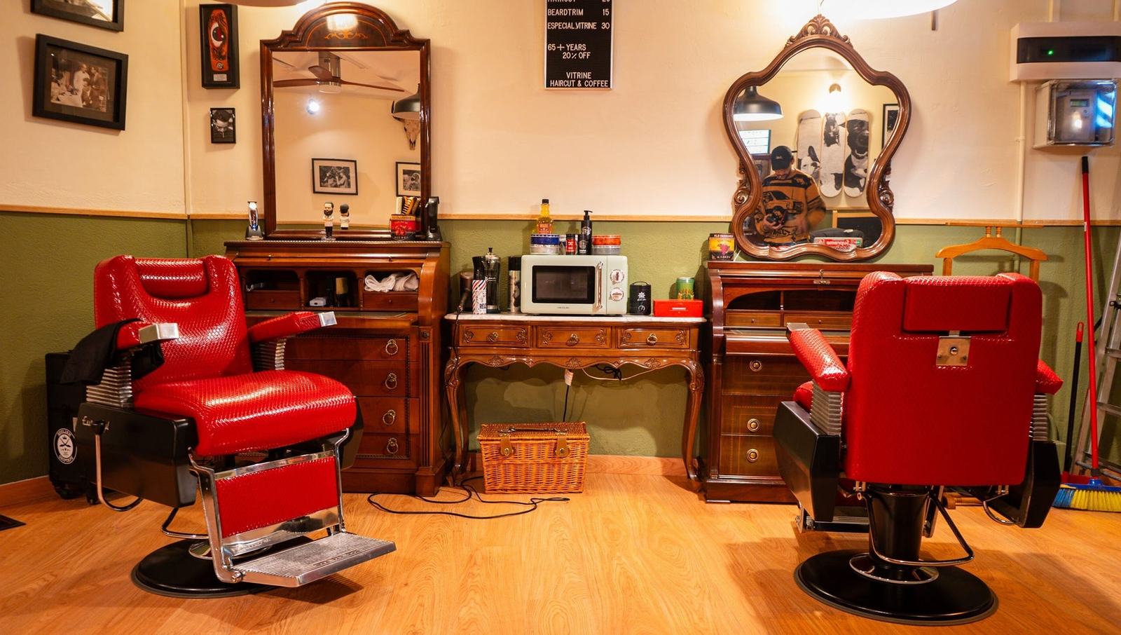 Puesto de trabajo del barbero con el sillón rojo, el espejo antiguo y los productos Reuzel